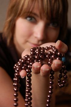 Girl holding brown pearl necklace, focus on hand