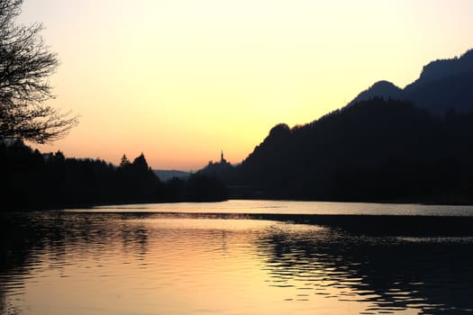 Lake, church and forest at a colorful sunset 