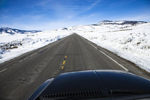 Perspective shot of car driving down road in snowy Colorado during winter.