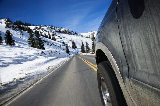 Perspective shot of SUV driving down road in snowy Colorado during winter.