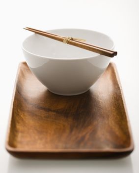 Asian bowl with chopsticks on wooden tray.