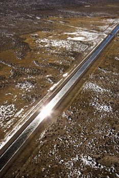 Aerial landscape of water canal running though rural Colorado with sun reflection.