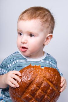 A little Caucasian boy eating a bread.big round loaf of bread of rustic bread
