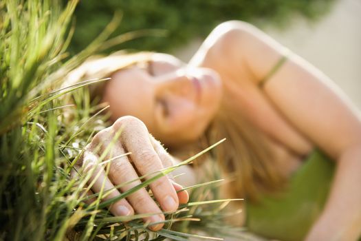 Selective focus portrait of young woman relaxing in grass.