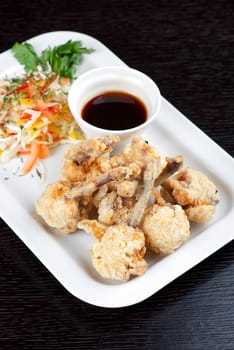 Fried chicken wings garnished with fresh vegetables with Teriyaki sauce