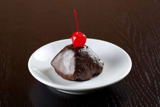 fresh baked chocolate cupcake with cherry on a wooden table