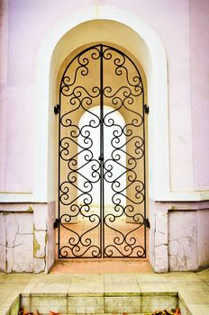 Facade an arch with the closed curly metal door. Isolated