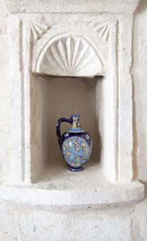 very ornate hand painted ceramic wine water jug with fish motif in ornamental man made limestone alcove