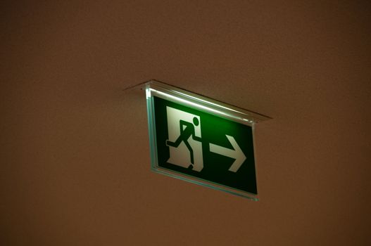 green emergency exit sign showing the way to escape