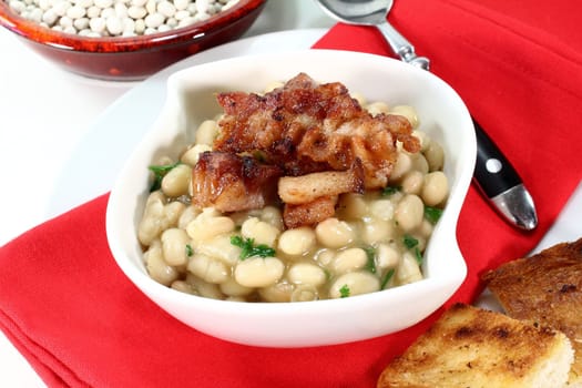 a bowl of white beans and fried bacon