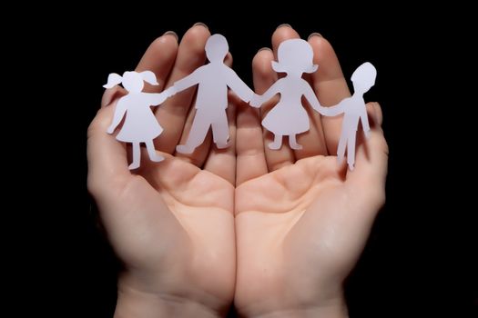 Paper chain family protected in cupped hands on black background