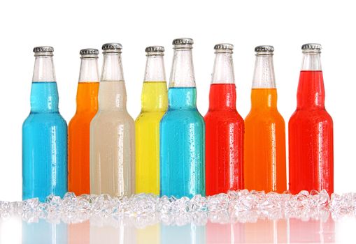 Bottles of multi-color drinks with ice on white background