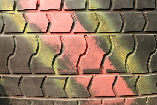 A fragment of an old automobile tire with the surface painted in different colors