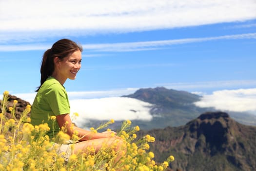 Hiker woman looking at view sitting on mountain top. Hiking on the peak of La Palma (Roque de los Muchachos), Canary Islands