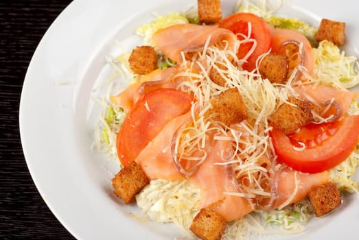 Salad of lettuce, chinese cabbage, tomato, garlic rusk, parmesan cheese, sauce and smoked salmon filet