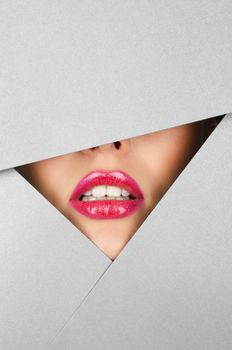 Beautiful female lips closeup behind silver paper background