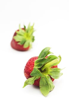 two strawberries, with one is in focus and one is in the background.