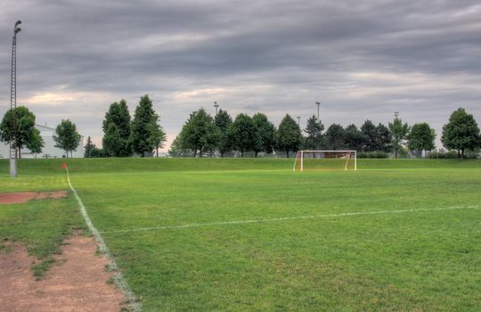 A cloudy unoccupied soccer field with trees in the background. (HDR photograph)
