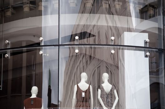 Modern boutique window with dressed mannequins as seen from outside