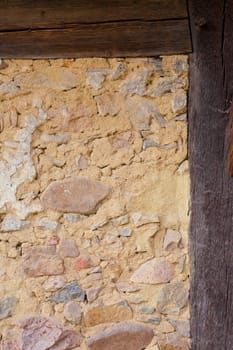 Architectural detail of historic half-timbered wall filled in with rocks and clay mortar.