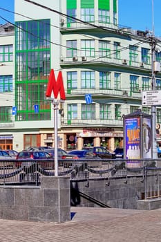 the entrance to the subway is a sign pointing to the underground against the background 
of a beautiful white building with green decor