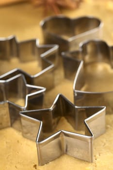 Christmas cookie cutters on dough (Selective Focus, Focus on the two front edges of the star-shaped cutter)