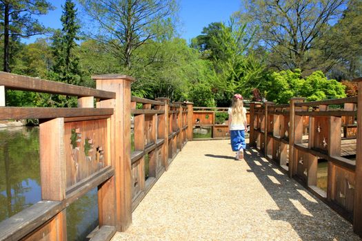 A little girl walking alone on a bridge