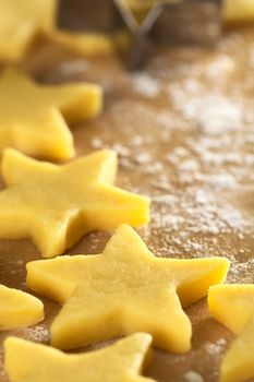 Unbaked star-shaped cookies on floured wooden surface (Selective Focus, Focus one third into the image)