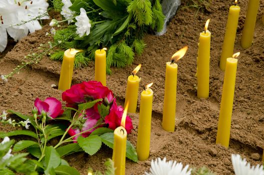 Candles cross burning on the newly formed grave.