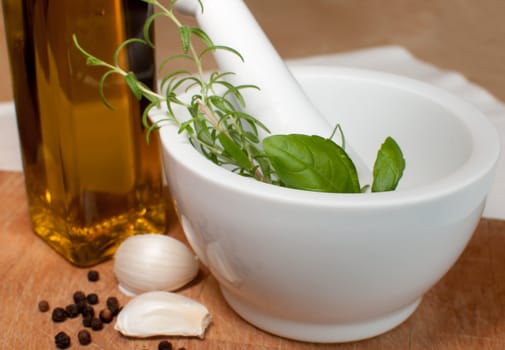 Preparation of marinade in Mortar - Rosemary, basil, garlic, pepper and olive oil on Chopping Board