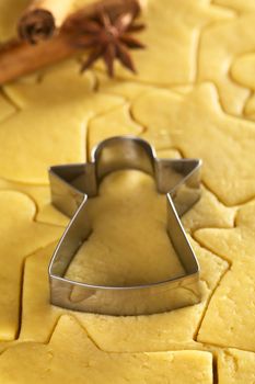 Cutting out Christmas cookies from shortcrust dough with an angel shaped cutter (Selective Focus, Focus on the lower edge of the cutter) 