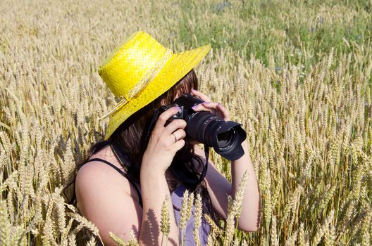 Young women taking shot of field full of wheat.