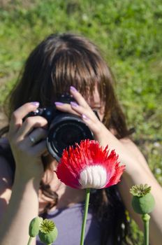 Young women taking shot of red white poppy.