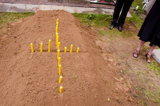 Cross formed from the candle on the newly stacked grave.