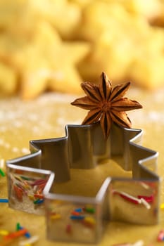 Star anise on Christmas tree shaped cookie cutter lying on dough with cookies in the back (Selective Focus, Focus on the middle of the anise) 