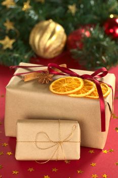 Christmas presents decorated with dried orange slices, cinnamon and anise (Selective Focus, Focus on the front of the orange slices and the ribbon on the small present)