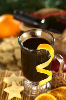 Hot spiced mulled wine garnished with orange peel (Selective Focus, Focus on the front rim of the glass and the orange peel at the rim)