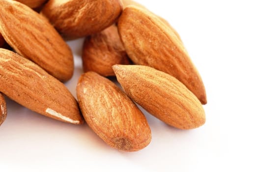 brown raw almonds over white background macro