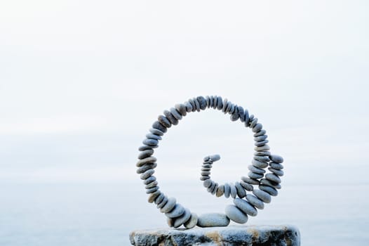 White spiral of pebbles on the boulder at the sea