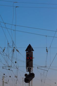 Red railway electric signal light and electric overhead contact wire all over.