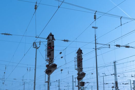 Red railway electric signal light and electric overhead contact wire all over.