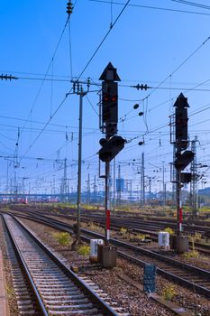 Red railway electric signal light and electric overhead contact wire all over a number of railway tracks.