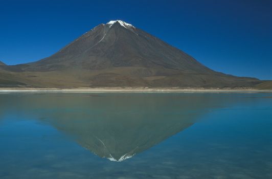 Snow capped peak of volcano Licancabur reflected in Laguna Verde. Bolivian Altiplano.