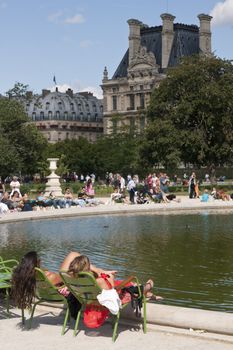 French women relaxing by an ornamental lake in the Jardin des Tuileries in Paris, France