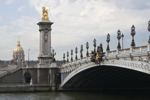 Historic bridge (Pont Alexandre III) over the River Seine in Paris, France. Gold of the Dome Church at Les Invalides in background.