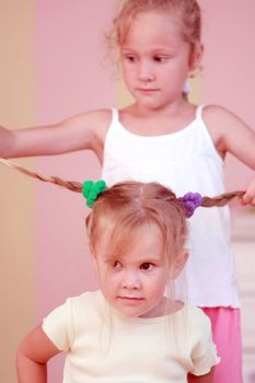 Small girl getting hair comb by sister at home