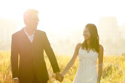 Bride and Groom holding hands, surrounding by natural morning golden sunlight.