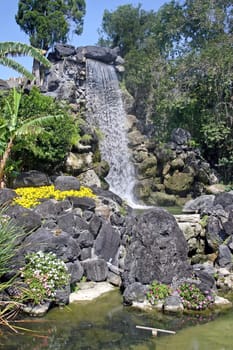 A waterfall and large rock feature in gardens