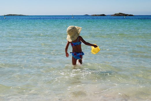 small girl with bucket in the ocean