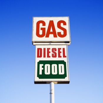 Sign against blue sky that reads gas, diesel and food.
